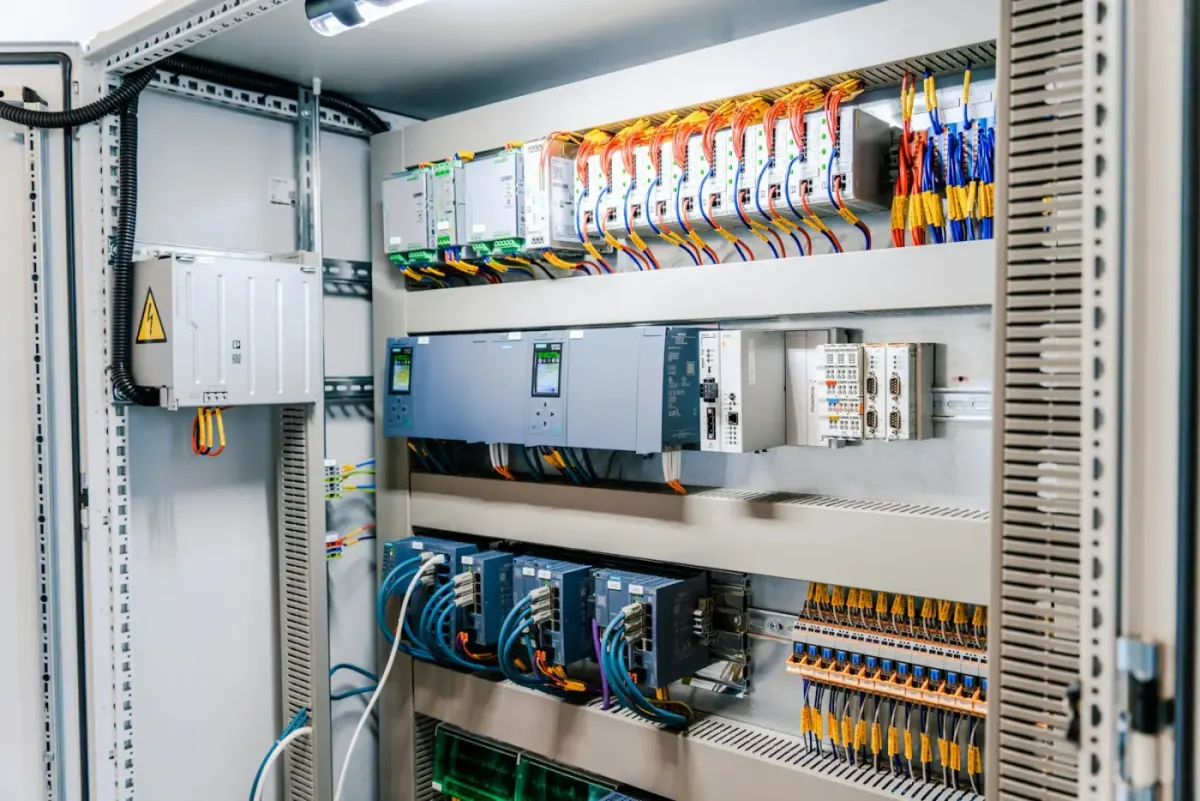 Armoire électrique ouverte avec automate programmable, modules et câblage sur rail